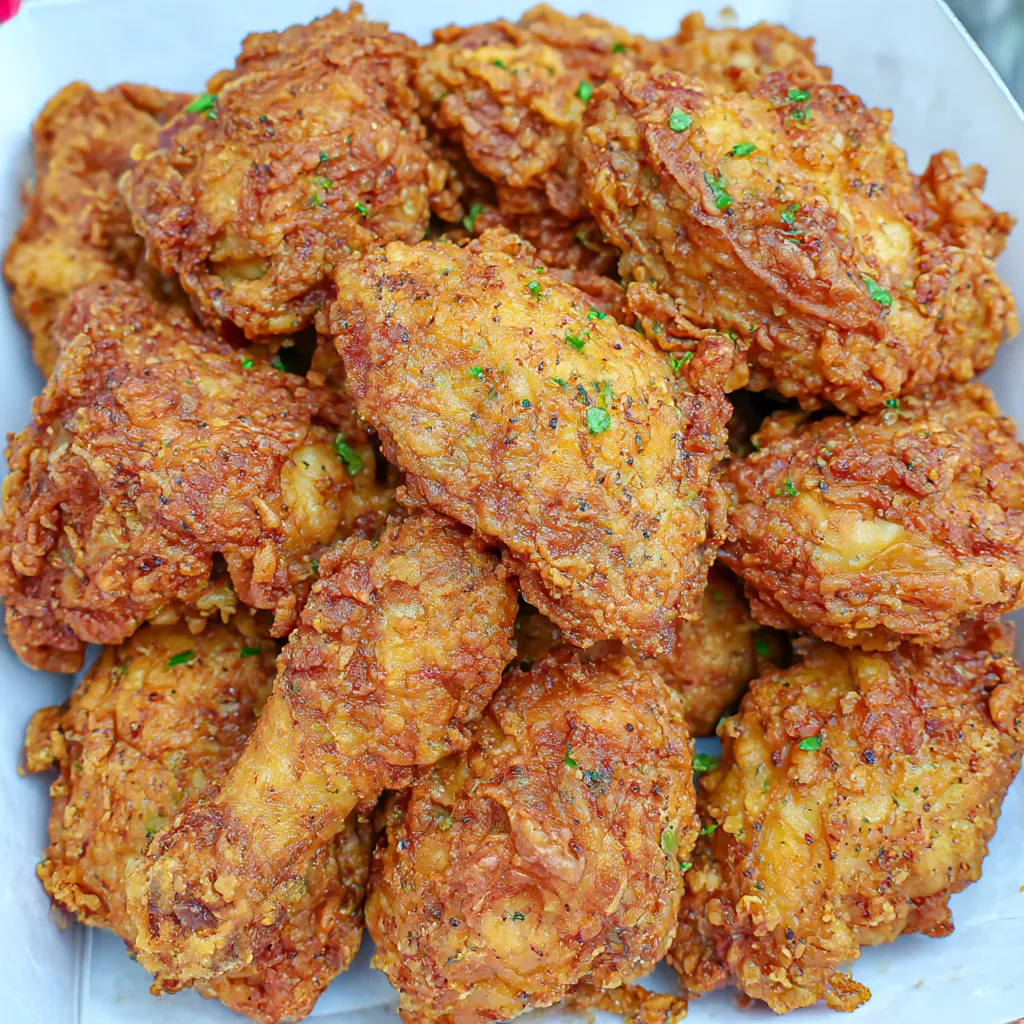 A plate of fried chicken with green herbs on top.